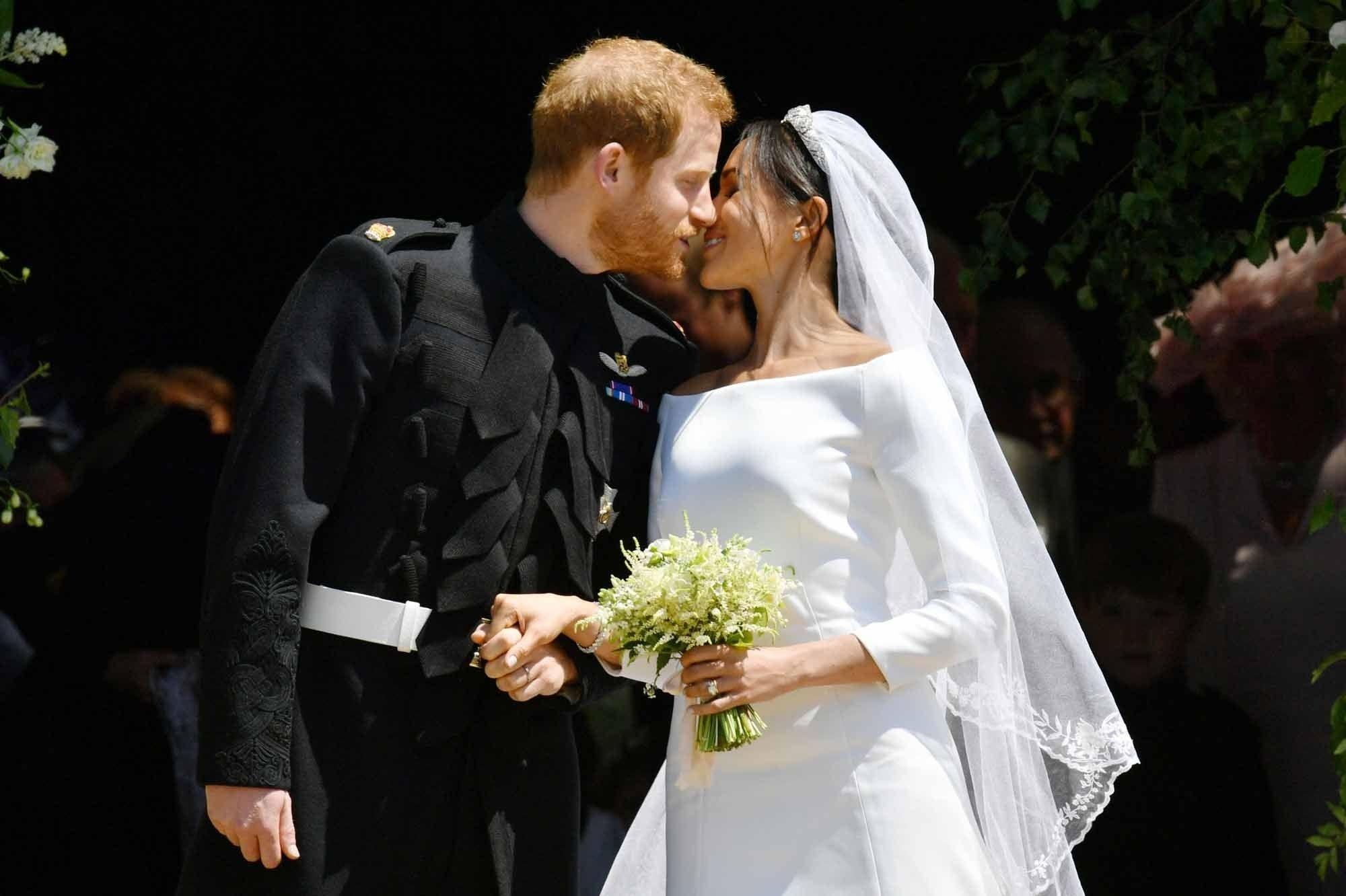 Britain's Prince Harry, Duke of Sussex kisses his wife Meghan, Duchess of Sussex as they leave from the West Door of St George's Chapel, Windsor Castle, in Windsor, on May 19, 2018 after their wedding ceremony. / AFP PHOTO / POOL / Ben Birchall