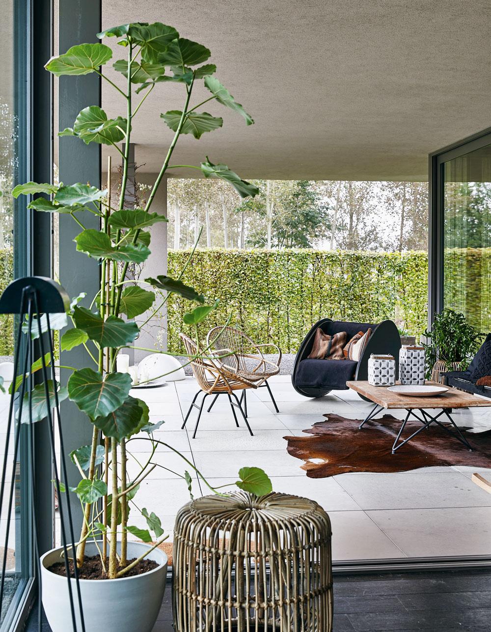 La terrasse couverte est un espace de vie supplémentaire aménagé à l'aide de mobilier en rotin vintage et d'un berceau transformé en siège, oeuvre de Linde Hermans.