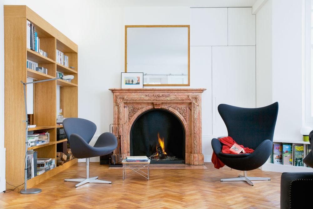 Au salon, la cheminée a été conservée et se marie avec les fauteuils Swan et Egg d'Arne Jacobsen et une bibliothèque sur mesure.