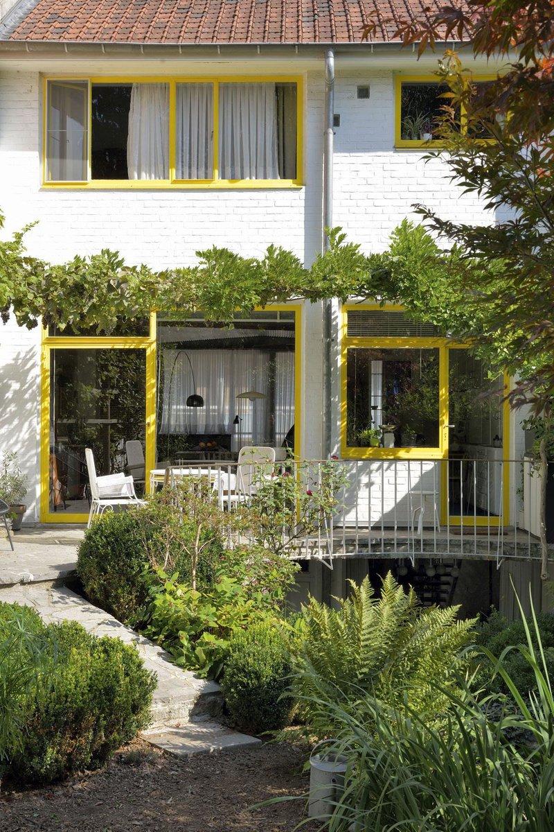 Côté jardin, la façade arrière est lumineuse avec ses châssis peints en jaune, agrémentée d'une petite terrasse orientée en plein soleil, sur laquelle sont disposées la table et les chaises dessinées par Jacques Dupuis, toujours en place aujourd'hui.