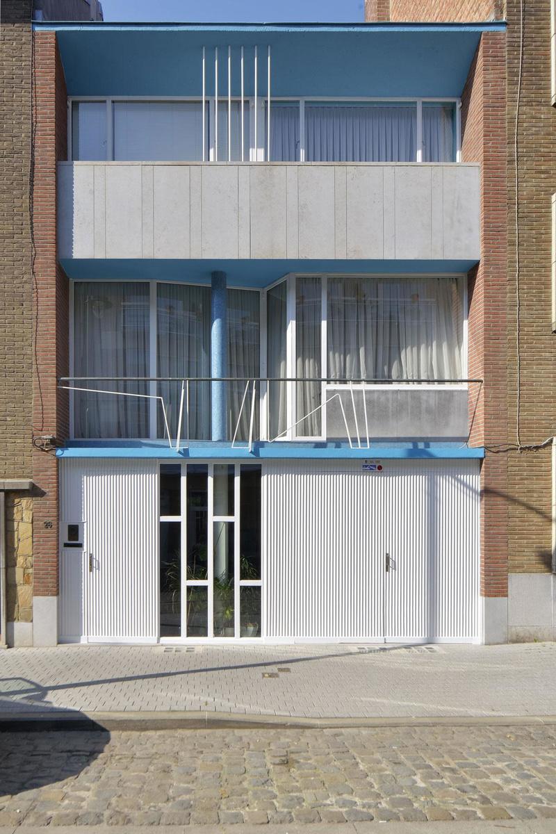 La façade côté rue se compose comme un tableau abstrait où le bleu et le blanc prédominent. Les vitres du premier étage se plient en paravent derrière une rambarde en fer au dessin d'oscillogramme.