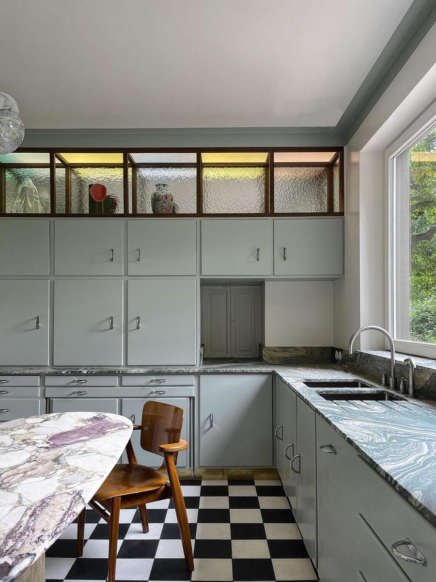 La cuisine d'une habitation, à Tervuren, composée d'une table en marbre, de meuble Cubex récupérés et de niches en noyer, cernées de verres colorés et martelés (2021).