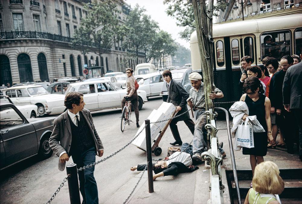 Paris, 1967             Révélation parisienne          En 1966 et 1967, Joel Meyerowitz s'offre un voyage en voiture à travers l'Europe. Paris compte parmi ses étapes. En pleine effervescence, la Ville Lumière agit sur lui comme un véritable révélateur. Plus qu'ailleurs, il peut être le flâneur, l'esprit libre regardant le monde qu'il a toujours rêvé d'être. Cette image témoigne certes d'un drame, mais pas forcément celui qu'on croit: le peu de poids du destin individuel face à la marche du monde.