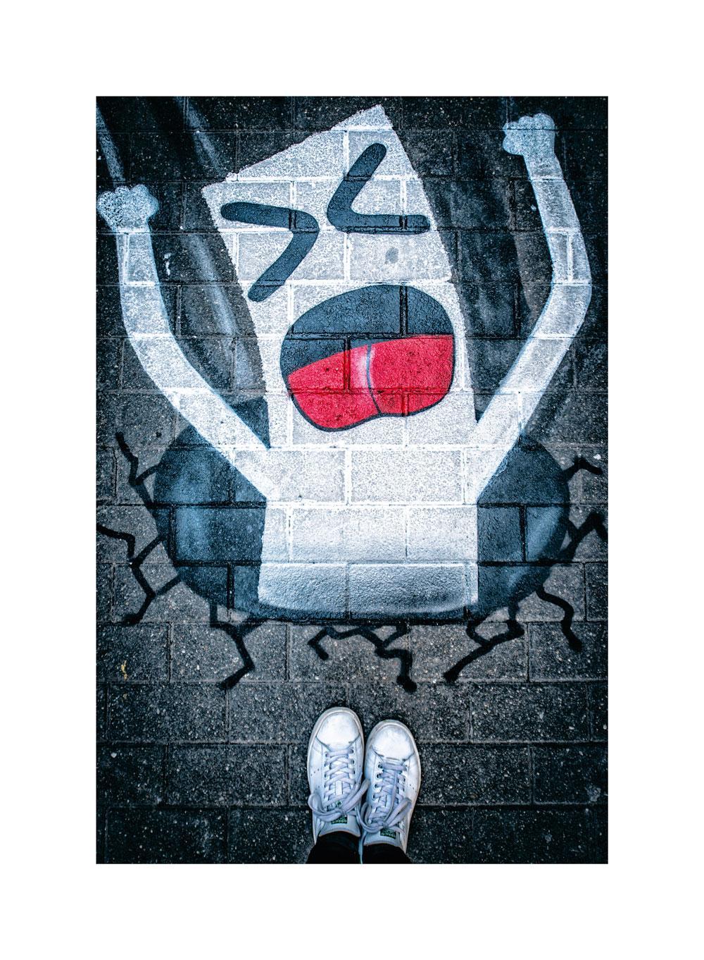 À deux reprises, le street artiste s'est amusé à ajouter des passages pour piétons dans les rues de Bruxelles, invitant à multiplier les flux plus lents dans une ville acquise aux logiques automobiles. Au 45 rue de Barchon, une bande blanche disparait dans un trou noir.