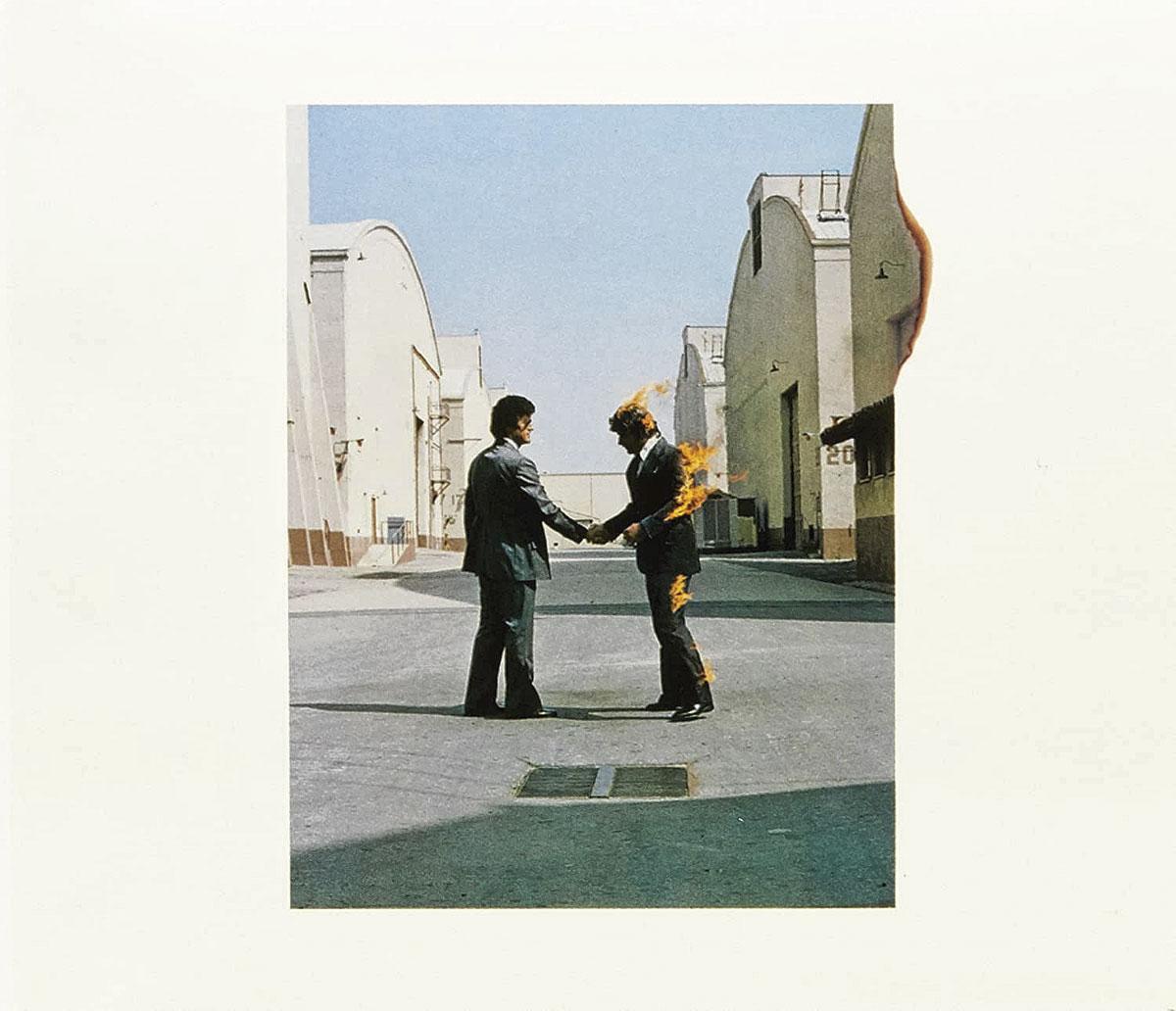 Pink Floyd  Wish You Were Here (1975) Sous pochette opaque noire ornée d'un autocollant, voilà un duo d'hommes flambés, deux cascadeurs pros.