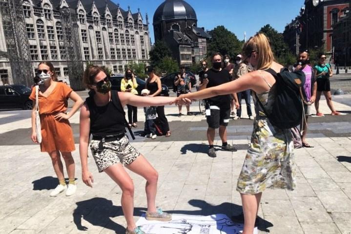 Deux manifestantes qui se tiennent la main lors de la performance sur la Place Saint-Lambert, à Liège.