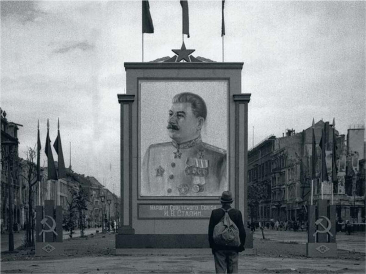 Un citoyen allemand regarde une vaste fresque à l'effigie de Staline sur l'Unter den Linden à Berlin, 3 juin 1945.