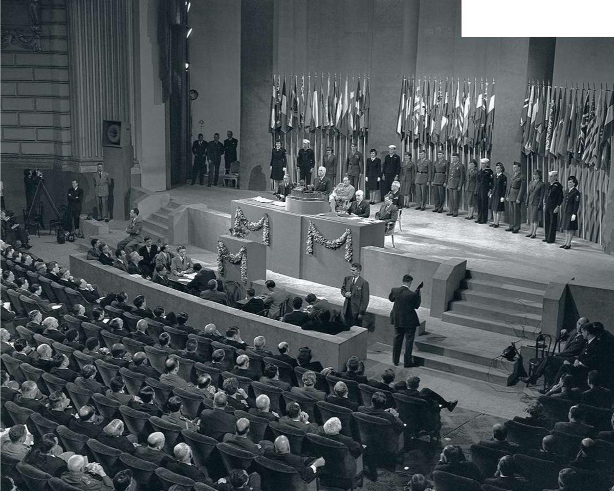 Après neuf semaines de débats, discours de clôture du président Harry S. Truman à la Conférence des Nations unies sur l'Organisation internationale. Une garde d'honneur de militaires américains se tient à l'arrière-plan, devant les drapeaux des nations.