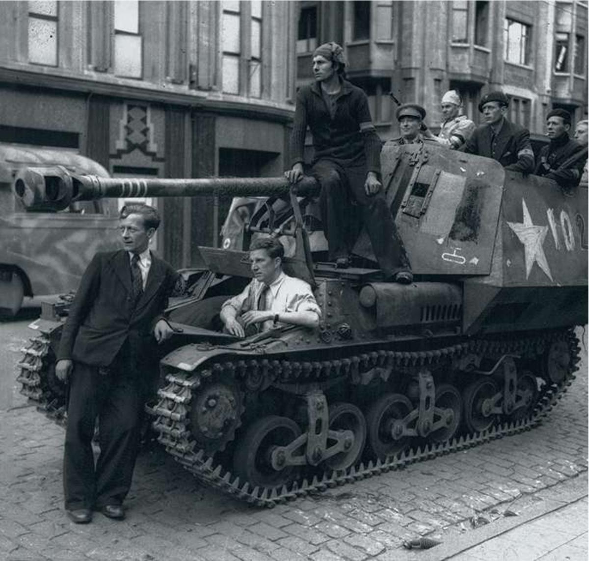 Des résistants belges posent sur un canon automoteur allemand saisi à Anvers à la fin de la Seconde Guerre mondiale.