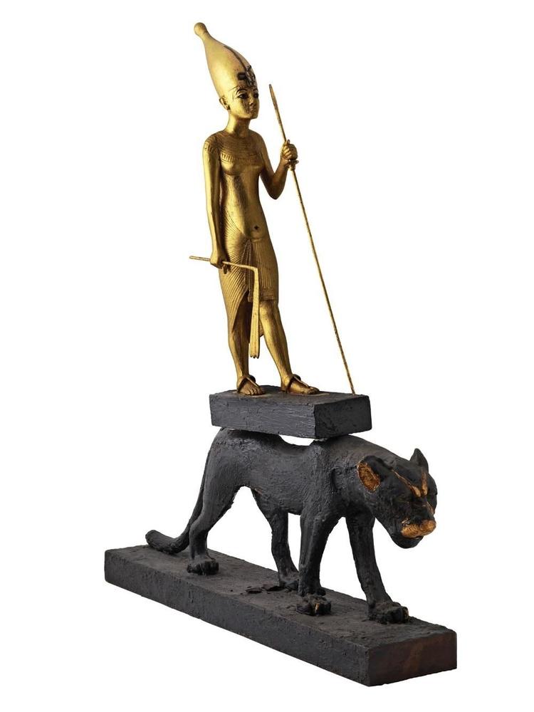 Féminine Exceptionnelle, cette statuette en bois dorée à l'or jaune (85,6 cm) représente le pharaon coiffé de la couronne blanche de Haute-Egypte, sur le dos d'une panthère, symbole du monde souterrain. Ses atours suggèrent qu'elle était initialement destinée à une femme - Néfertiti ou Mérytaton, selon les spécialistes.