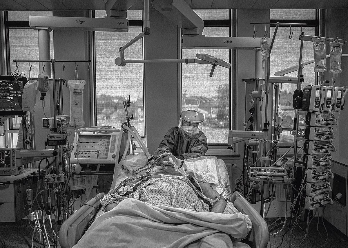 Un infirmier prodigue des soins à un patient intubé, aux soins intensifs du CHU Tivoli.
