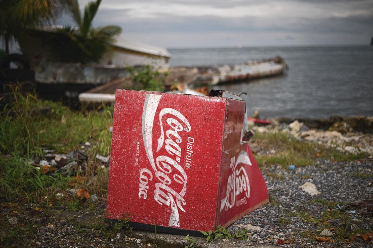 Comme un symbole de l'ascendance nord-américaine croissante, la carcasse d'une glacière Coca-Cola abandonnée sur la rive du rio Dulce, à quelques centaines de mètres des hôtels les plus éloignés du centre.