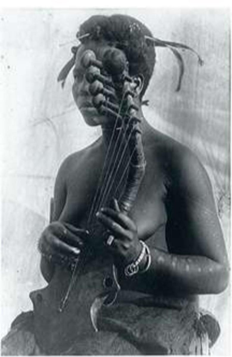 Une femme de culture vungura joue du kundi, un instrument à cordes.