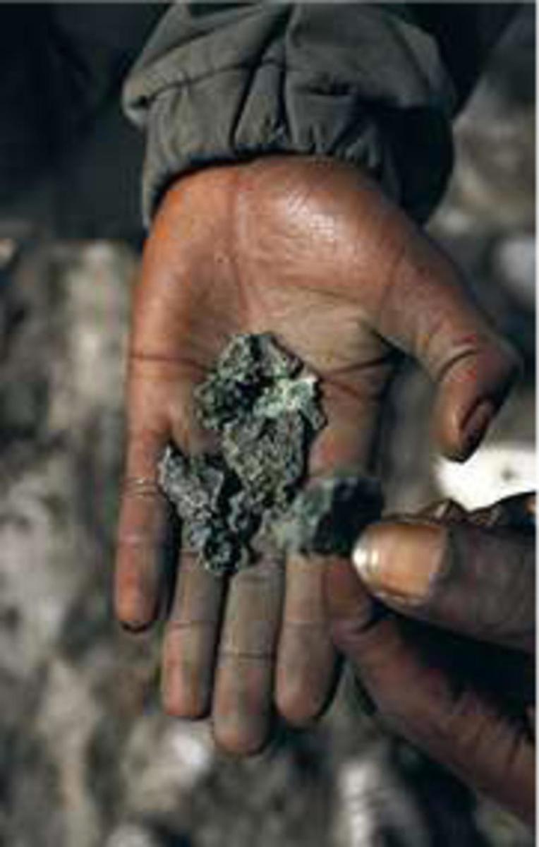 Une main de mineur présente du minerai de cuivre.