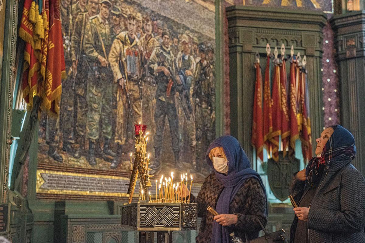 Des croyantes suivent les rites orthodoxes. Derrière elles, une mosaïque en l'honneur des soldats engagés dans les différents conflits mondiaux, notamment en Syrie.