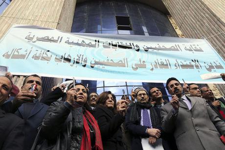 Journalisten houden pennen omhoog tijdens een stil protest tegen terrorisme en in solidariteit met de slachtoffers van de aanslag op Charlie Hebdo, voor de persvakbond in Caïro, Egypte. Op de banner staat dat de vakbond 'misdaden tegen journalisten en terrorisme in al zijn vormen' veroordeelt.