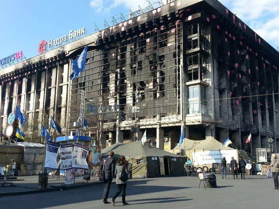 Kiev, in april 2014. Links de Europese vlaggen, voor een door rellen uitgebrand gebouw.