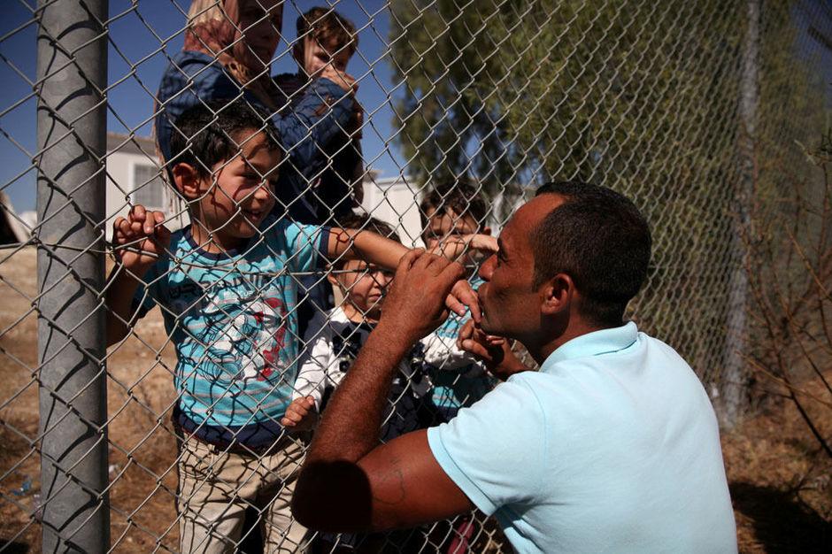 Een vader kust de hand van zijn zoon nadat ze zijn herenigd in een vluchtelingenkamp in Cyprus