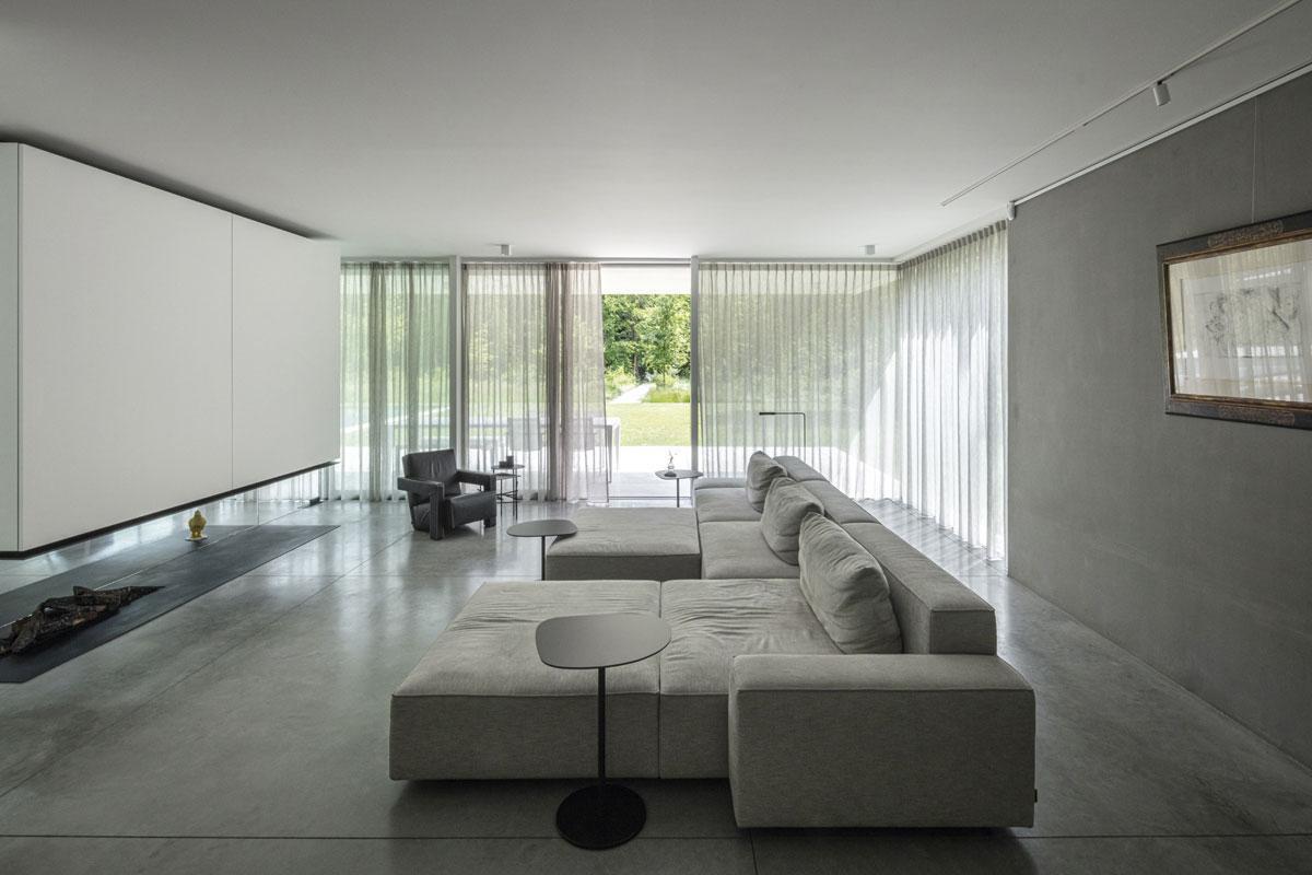 De strakke belijning werd uitgewerkt door Govaert-Vanhoutte Architects. Dat gaat ook over details. Zo loopt de lijn in de betonnen vloer voor de sofa van Cassina gelijk met de linkerkant van het wandelpad verderop in de tuin.