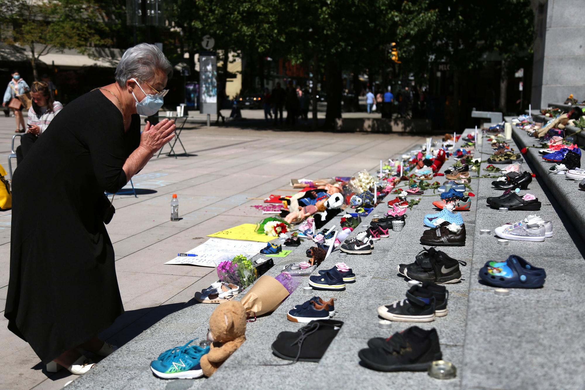 Mei 2021: een vrouw legt bloemen neer aan de trappen van de Vancouver Art Gallery, waar ter nagedachtenis van de zopas teruggevonden slachtoffers 215 paar schoenen werden neergezet.