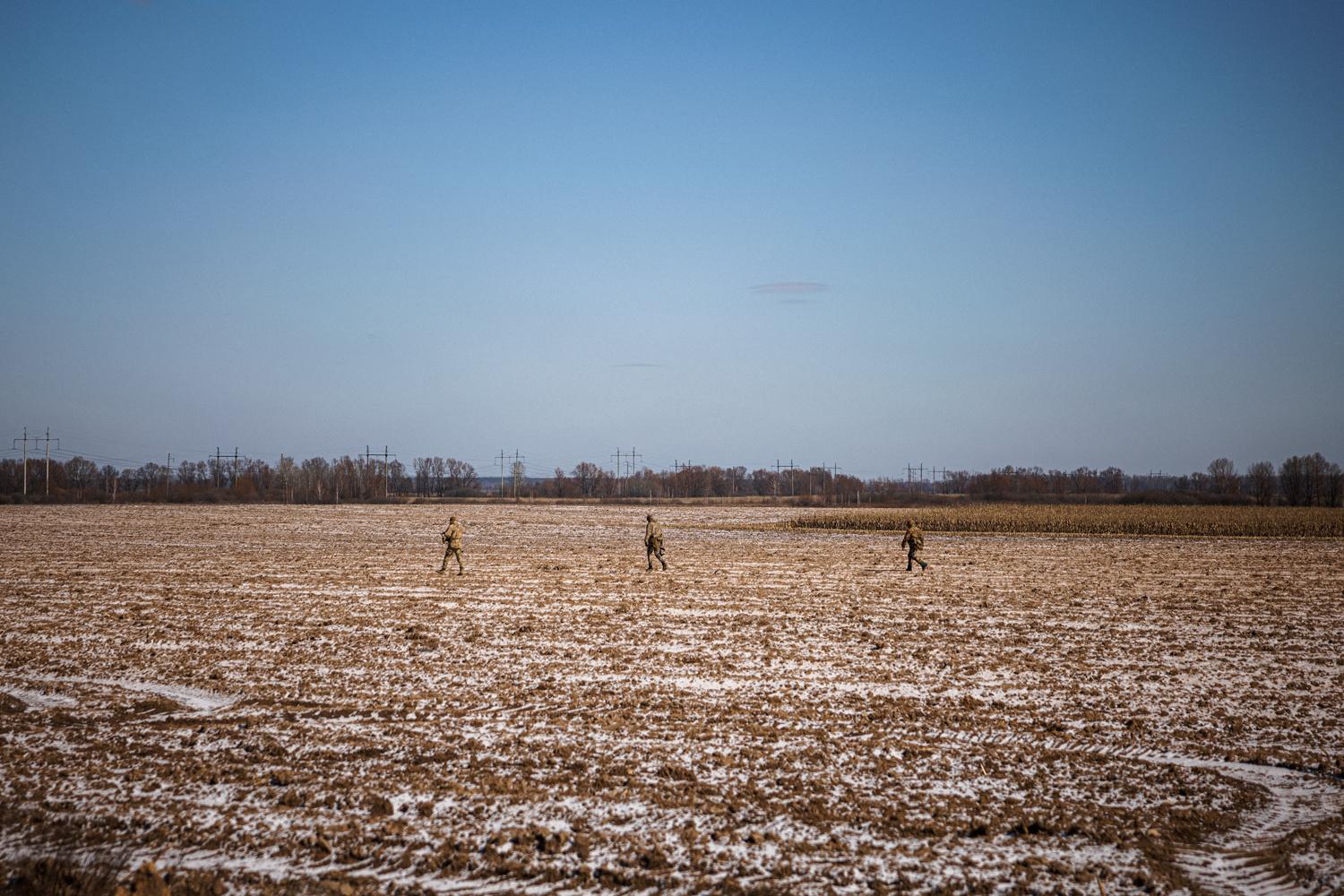 Des militaires ukrainiens marchent dans un champ près du village de Velyka Dymerka, à 40 km à l'est de Kiev, le 10 mars 2022.