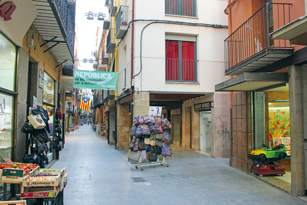 De Carrer d'Avall, de winkelstraat waar de familie Martínez Montoliú een schoenenzaak bezat. De zaak is nu een prullenwinkel voor kinderen (uiterst rechts te zien).