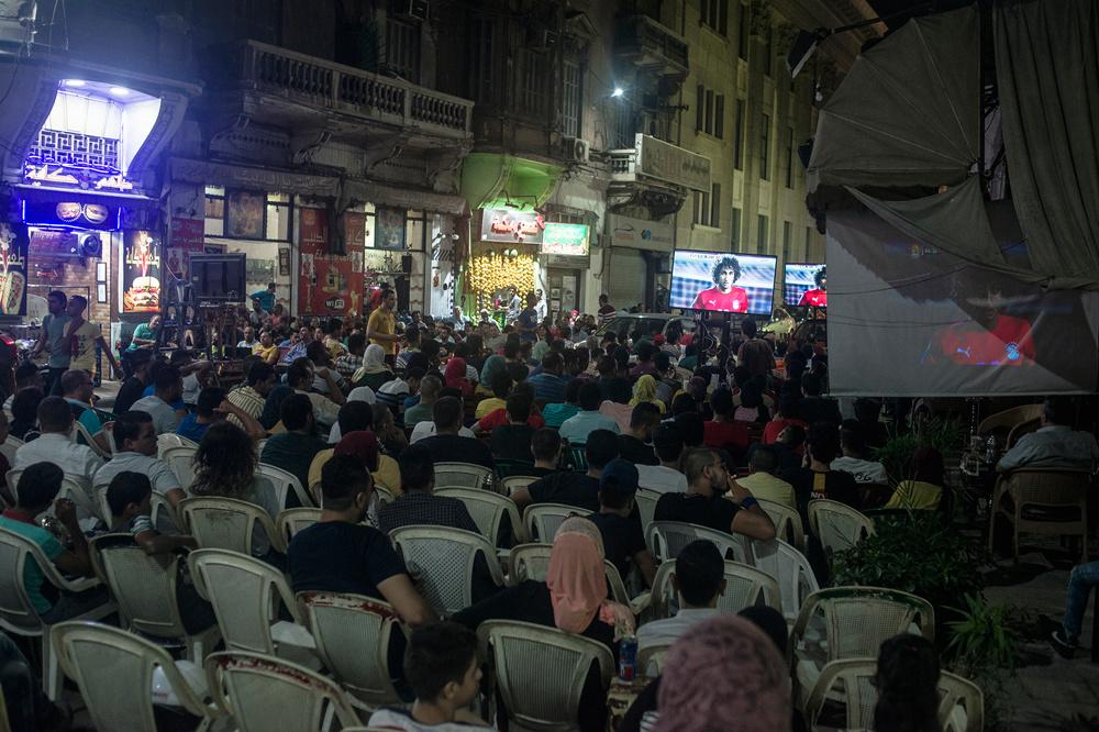 Egyptische fans bekijken de match in de straten van Alexandria. Amr Warda verschijnt op het scherm.