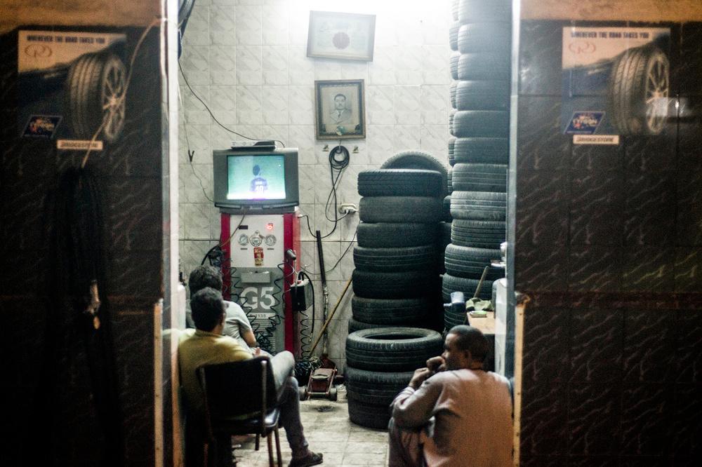 Medewerkers van een bandencentrale in Alexandrië volgen een wedstrijd op televisie.
