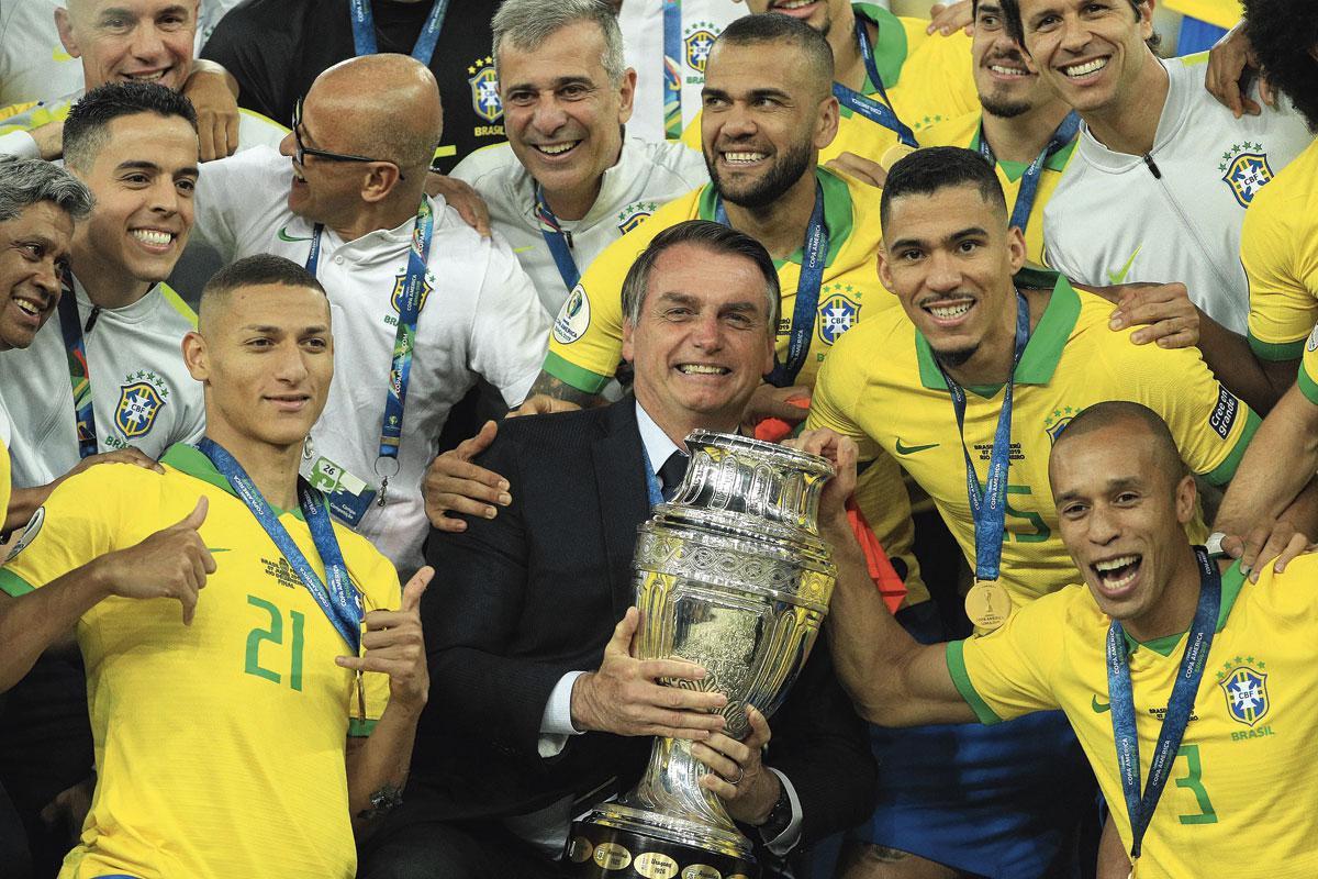 Een beeld uit de Copa América van 2019 toen Brazilië in eigen land won, met een glunderende Bolsonaro tussen de spelers.