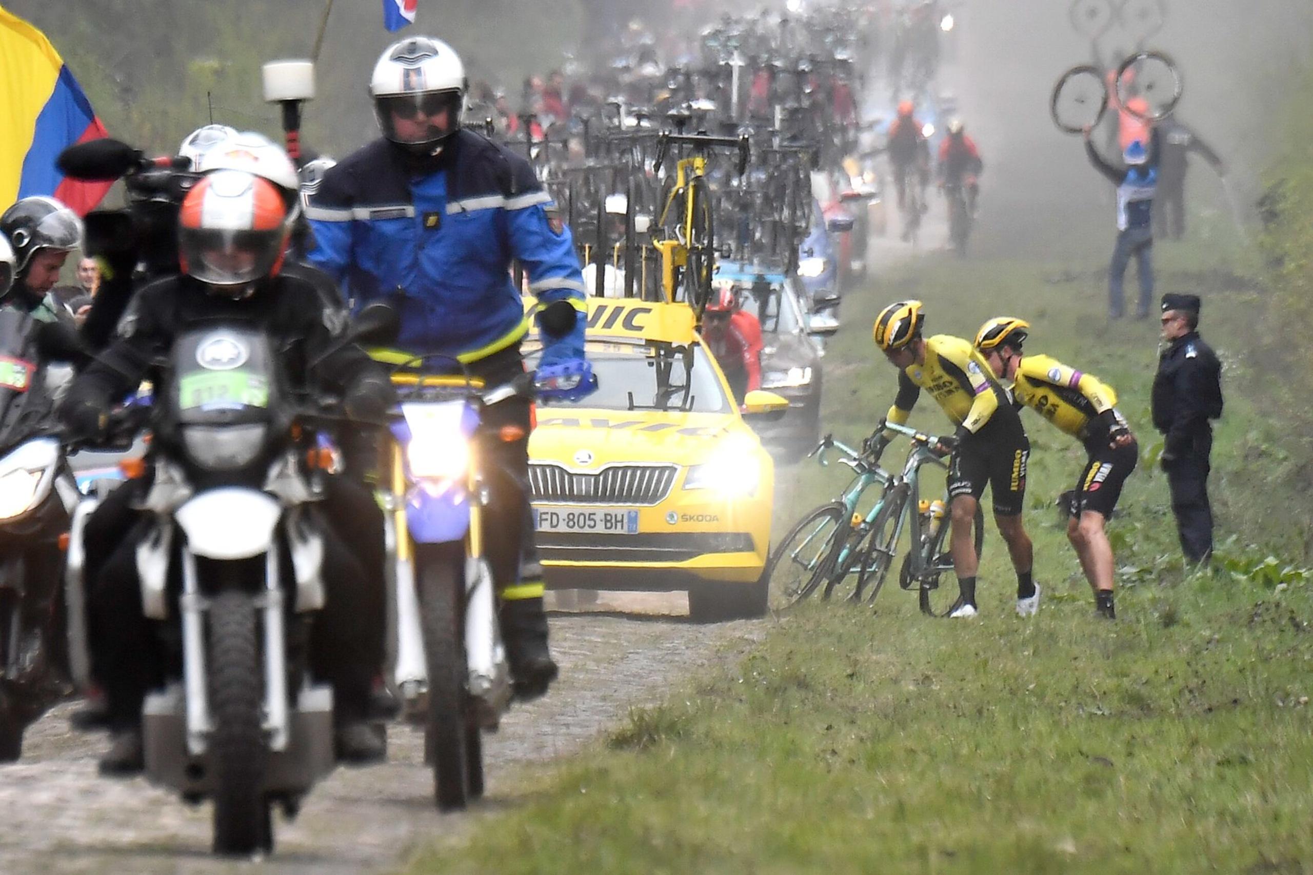 Wout van Aert rijdt lek in Trouée d'Arenberg en wisselt met een ploegmaat van fiets. 