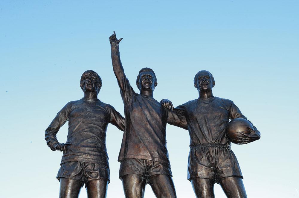 Het standbeeld van George Best, Denis Law en Bobby Charlton aan Old Trafford.