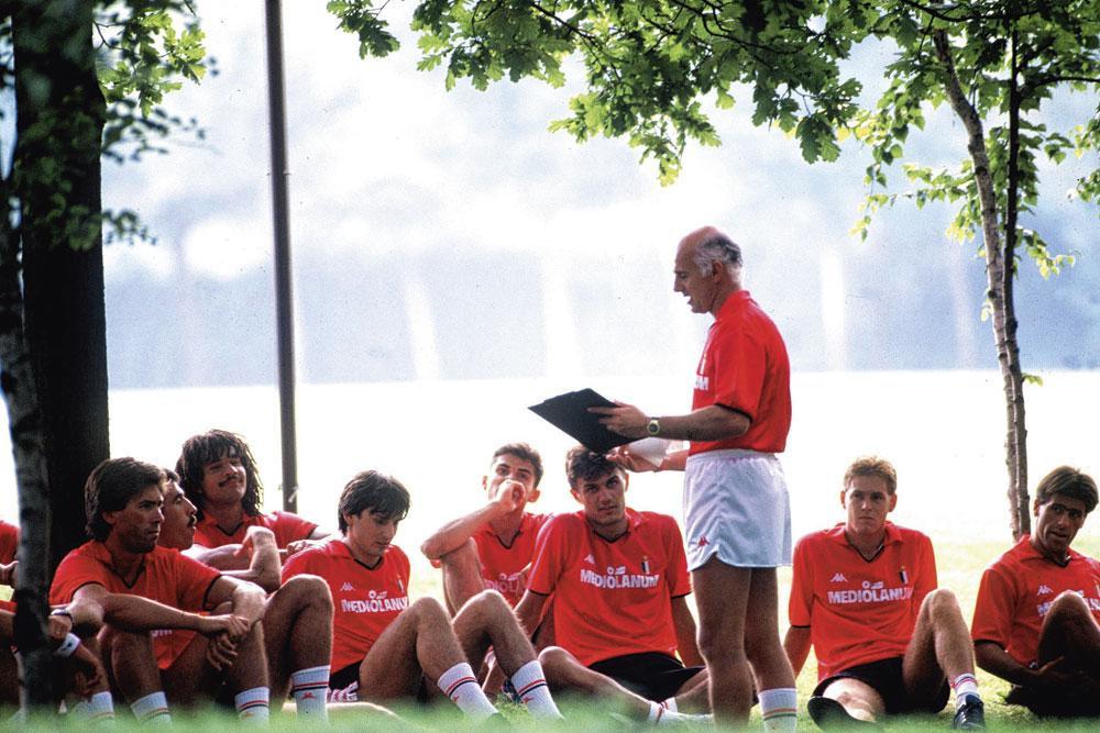 Arrigo Sacchi doceert voetbal. Paolo Maldini zit in het midden aandachtig te luisteren.