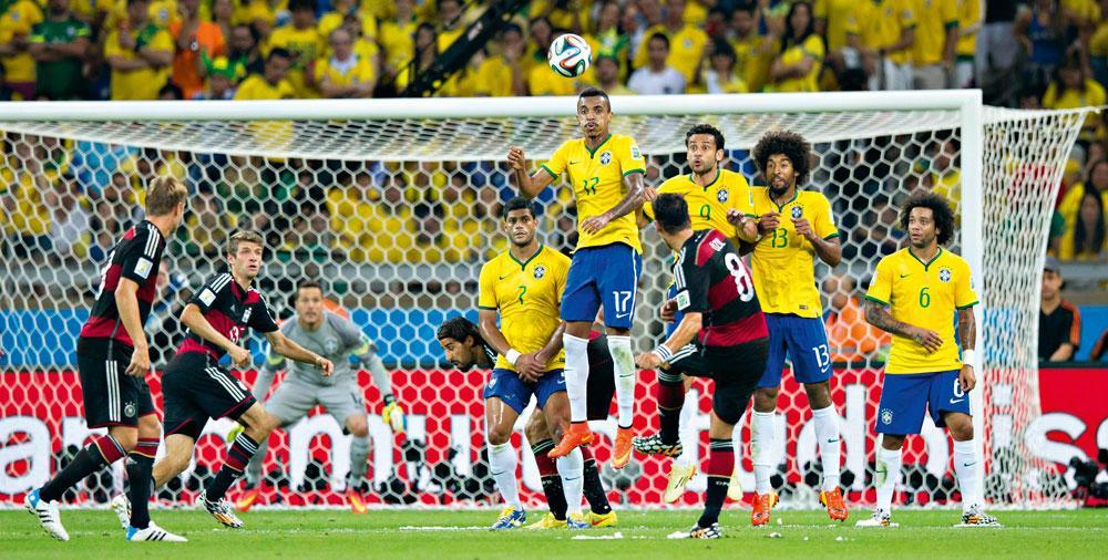 Mesut Özil mikt een vrijschop over het Braziliaanse muurtje, waar Luiz Gustavo het hoogst springt.