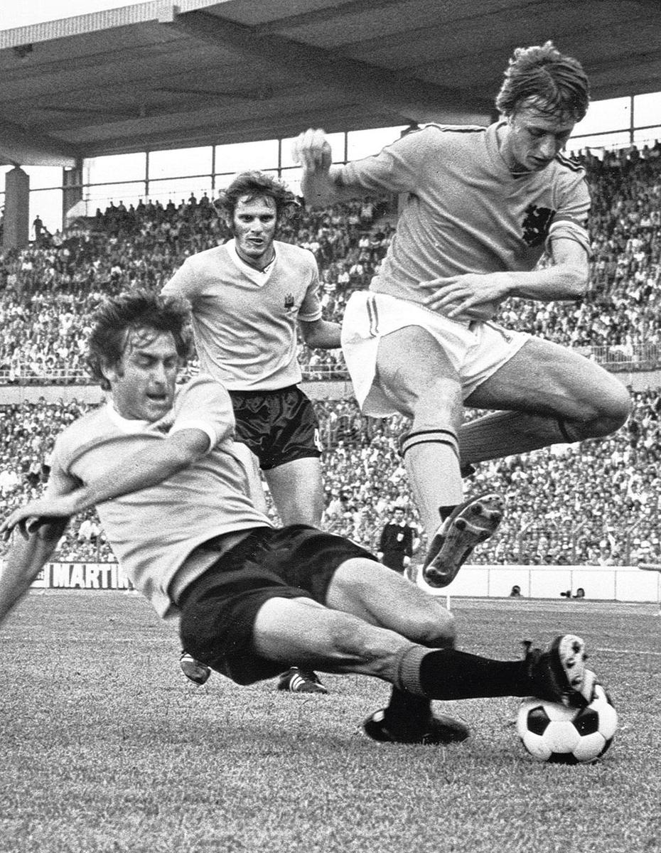Johan Cruijff ontwijkt een stevige tackle tijdens Nederland-Uruguay op het WK'74.