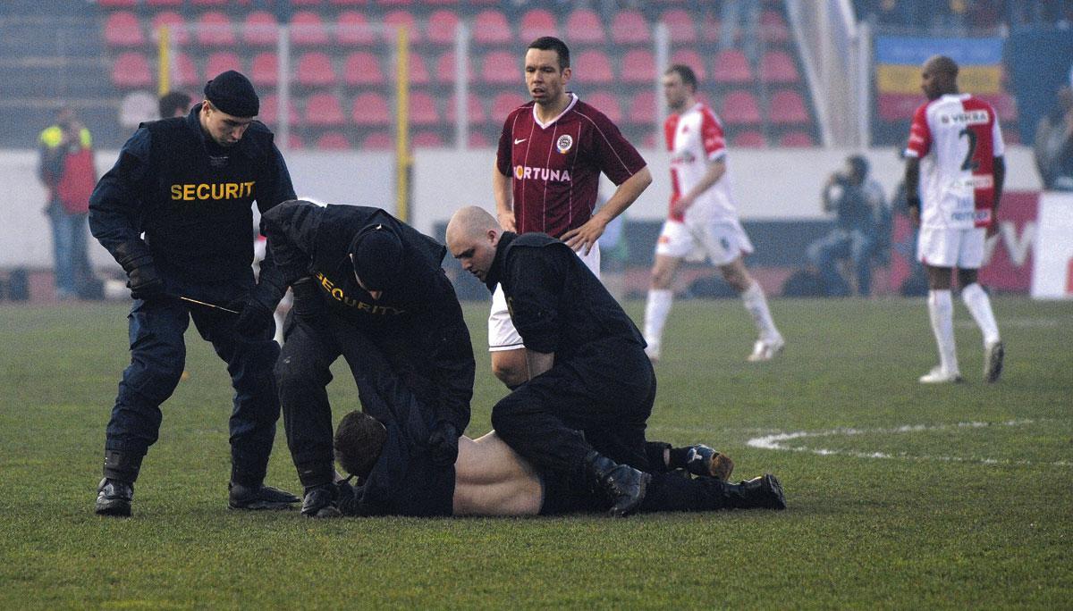 Des agents de sécurité maîtrisent un supporter qui a pénétré sur la pelouse durant un Slavia Prague - Sparta Prague.