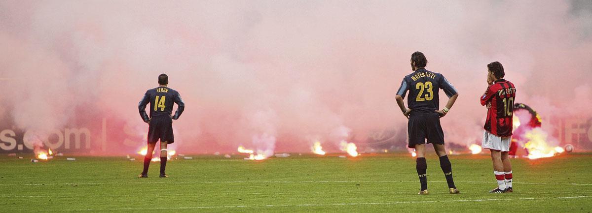 Un instantané d'un derby milanais de 2005: il pleut des fumigènes depuis les tribunes sous les regards de Juan Sebastián Verón, Marco Materazzi et Rui Costa.