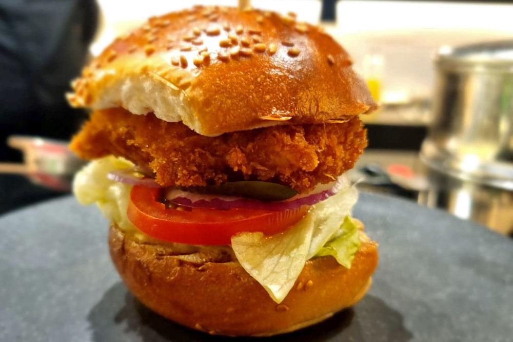Mis en valeur dans ce qui s'apparente à un burger 'gourmet', le poulet est frit et entouré de panure.