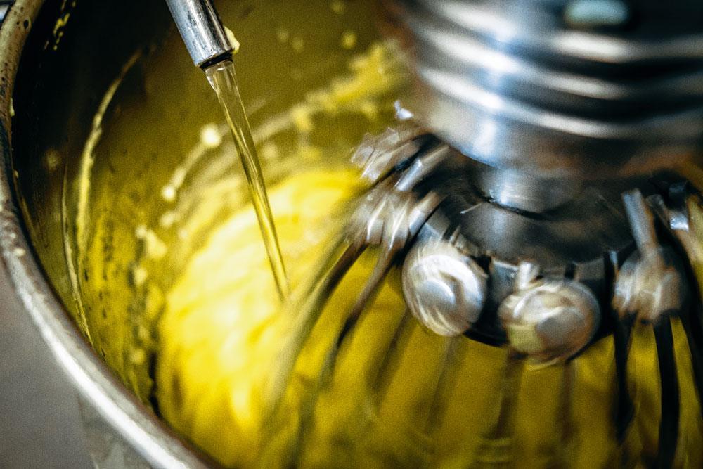 3 Kloppen - Terwijl de kloppers de mosterd en het eigeel opkloppen, loopt geleidelijk 20 liter zonnebloemolie bij het mengsel. Na twintig minuten is de mayonaise klaar. 