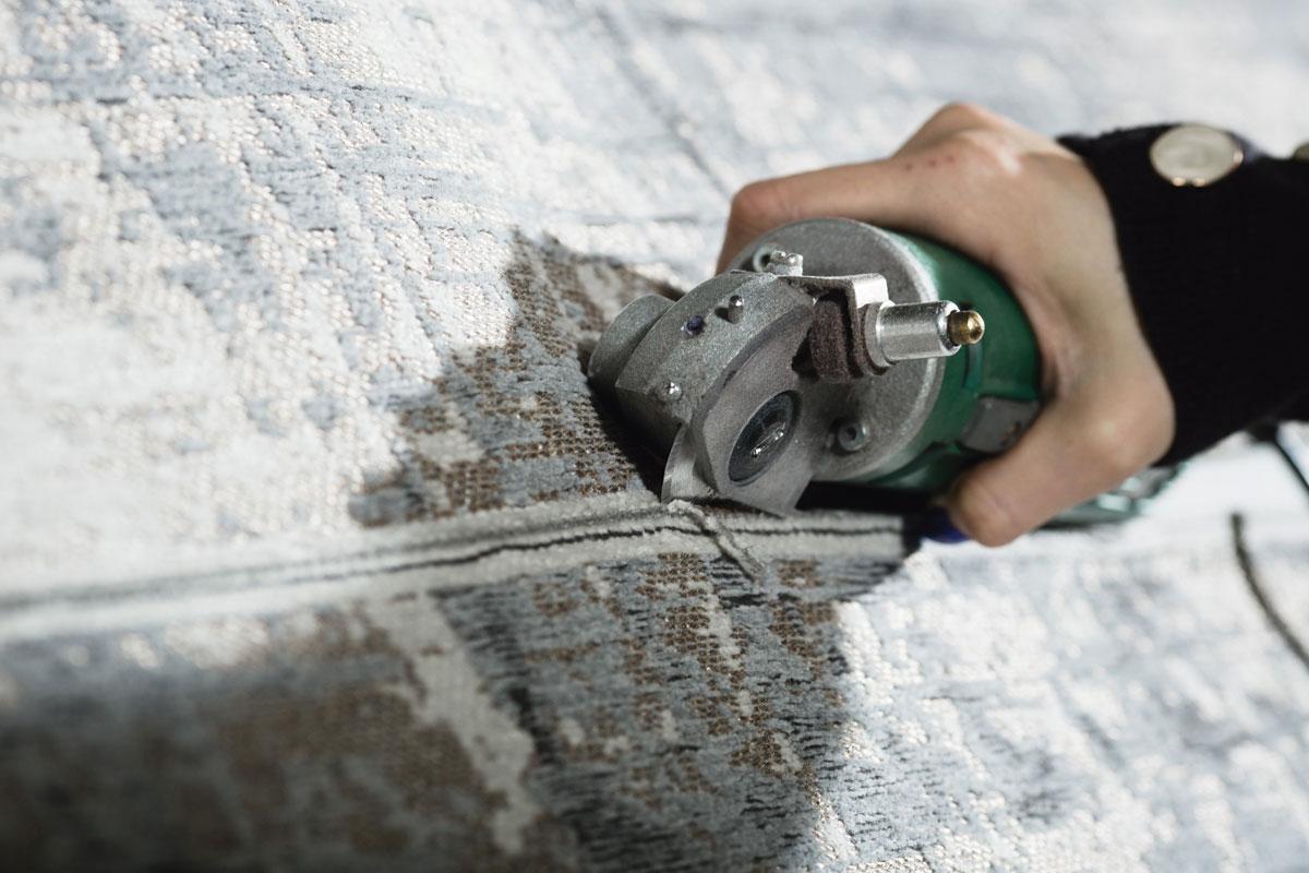 Snijden - Na het weven wordt op de onderzijde een antisliplaag van latex aangebracht. Vervolgens wordt het 25 tot 50 meter lange tapijt versneden tot de gewenste formaten, inclusief kleine vierkante stalen die worden geleverd aan de tapijtwinkels om aan klanten te tonen.