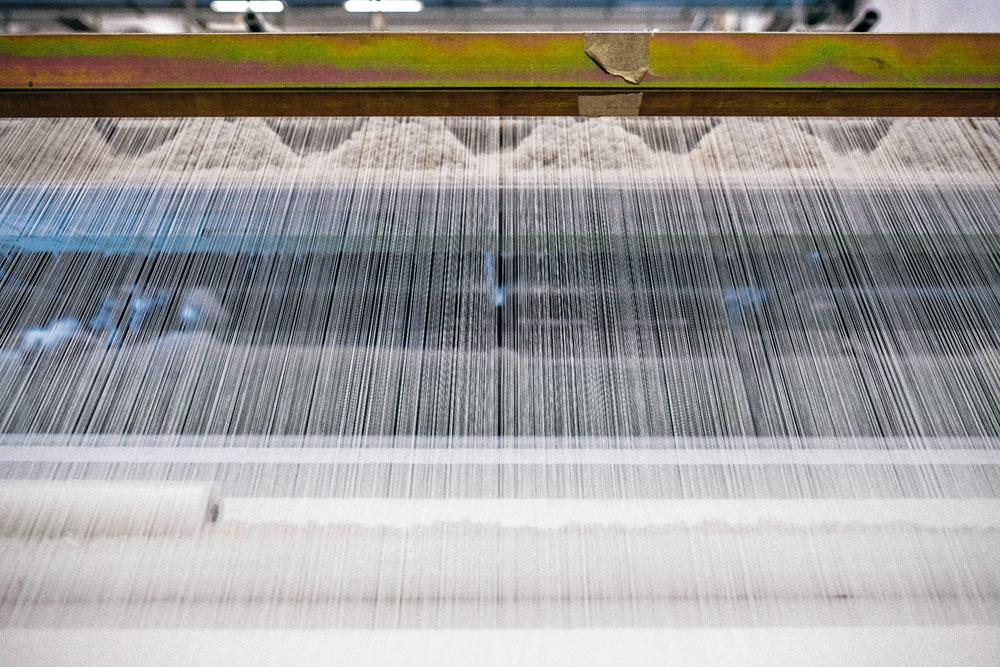 2 Kettingbomen - De kettingdraden zitten op grote spoelen, kettingbomen genoemd. Ze zijn altijd wit, de basiskleur van Squid. Elk rijtje telt 3260 draadjes. Per minuut trekt de Jacquard-weefmachine die 3260 kettingdraden 400 keer omhoog.