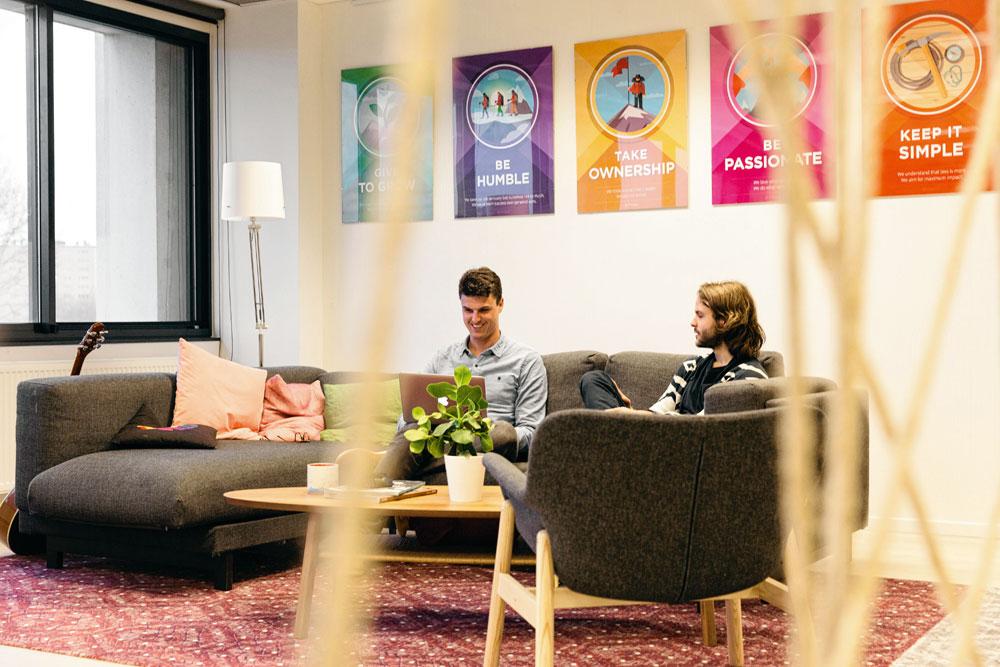 Showpad investeert in een gezellige en opvallende werkomgeving. Dat is niet vanzelfsprekend in een klassiek kantoorcomplex. De keuze viel op een warme, huiselijke sfeer met tapijten, hout, veel kleur en planten.