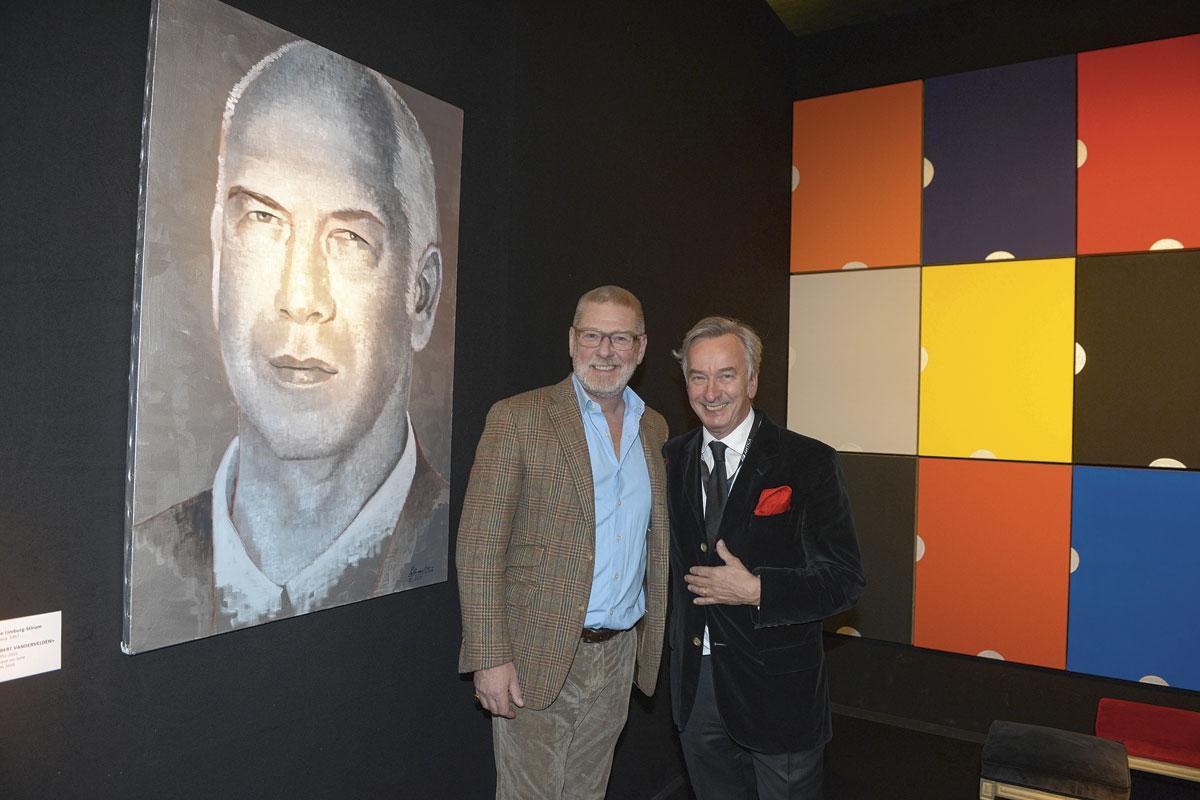L'ensemblier-décorateur Gérald Watelet et l'antiquaire Ton Laaracker devant un portrait de l'antiquaire liégeois Albert Vandervelden, qui nous a récemment quittés.