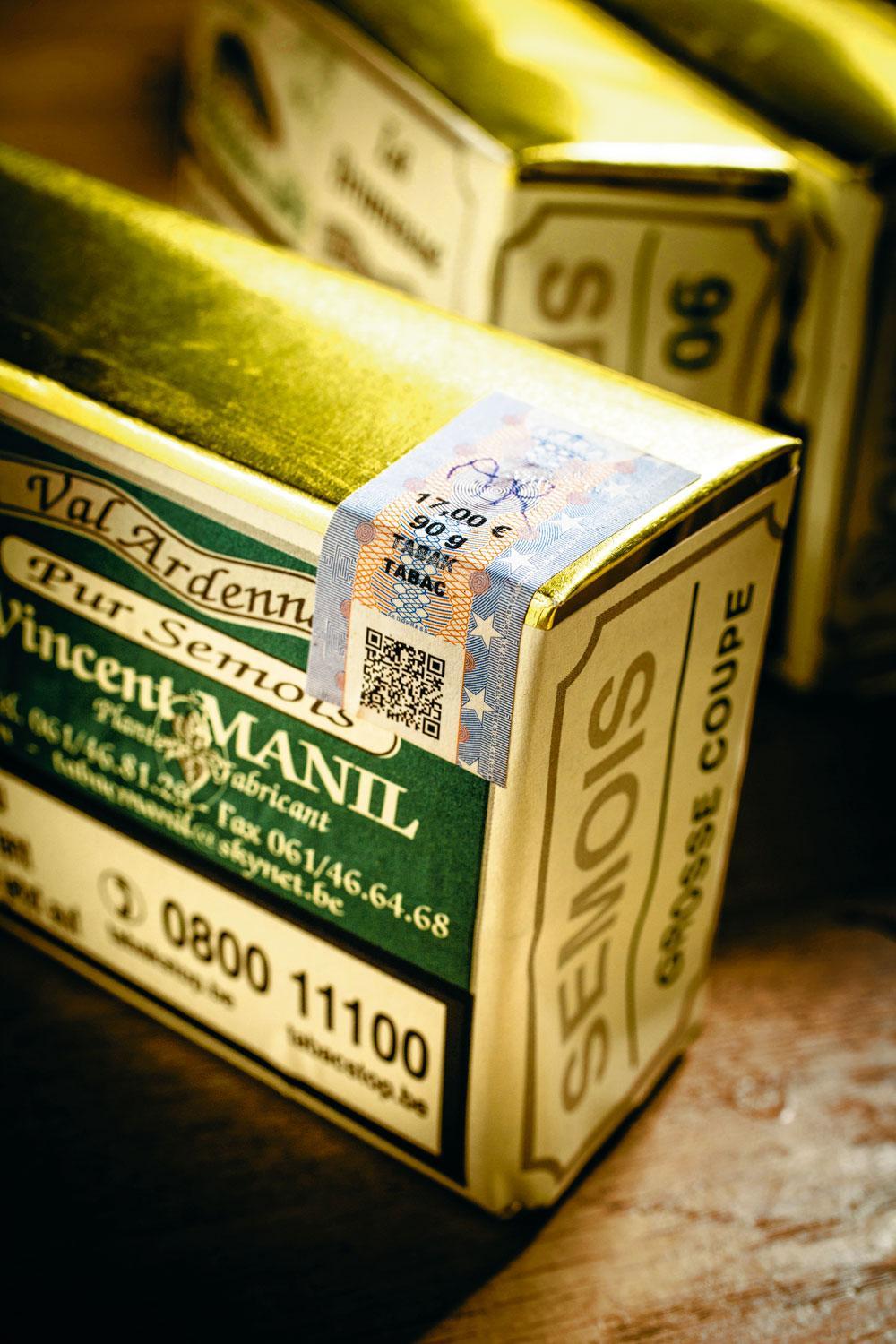 7. L'emballage - Les paquets dorés sont désormais fermés. Ne reste plus à l'artisan qu'à appliquer son étiquette. Une opération également réalisée à la main,  à l'aide d'un pinceau et de colle. Enfin, puisque la vente du tabac est l'objet d'une taxation spécifique, une bandelette fiscale est également apposée  sur les paquets destinés au marché belge.