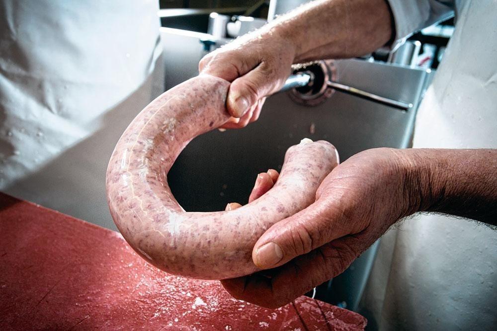 4 L'embossage. Comme son nom l'indique, l'embossage est l'opération qui consiste à pousser la viande hachée dans le boyau. Contrairement à la plupart des autres produits de la maison, les colliers sont confectionnés à partir de boyaux naturels de boeuf, fournis par quelques sociétés spécialisées. Les boyaux de boeuf sont plus souples que ceux de porc ; ce sont eux qui permettent de donner une forme ronde au collier. Après embossage, un boucher coupe le boyau, fait un noeud et pend le collier à un chariot. Pour les plus grands saucissons, ceux qui pèsent plusieurs kilos et sont uniquement destinés aux trancheuses, la société utilise également parfois des boyaux synthétiques.