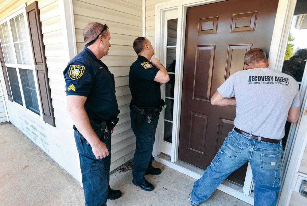 A Bethlehem (Géorgie), des policiers font ouvrir la porte d'une maison saisie dont il vont vider les meubles et changer la serrure (2011).