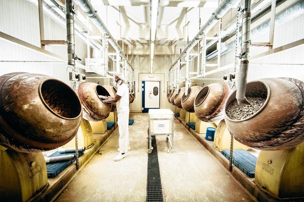4. Le gommage - Les morceaux de chocolat sont ensuite disposés dans les turbines, sortes de bétonneuses en cuivre qui mélangent les ingrédients et homogénéisent les dragées. La gomme arabique est ajoutée en premier. Celle-ci fera office de colle. Une première couche de sucre impalpable est ensuite insérée.