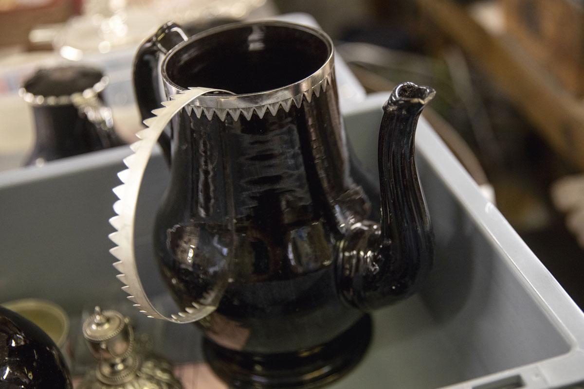 DANS UN COIN DE L'ATELIER, une magnifique cafetière en porcelaine du 18e siècle dont il faut refaire le pied en métal.