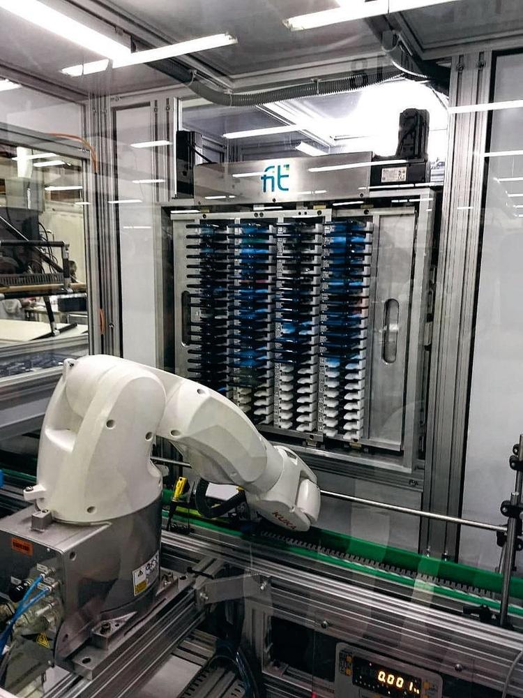 Un bras de robot place le smartphone semi-fini dans un tiroir où les fréquences sont testées avant de poursuivre l'assemblage.