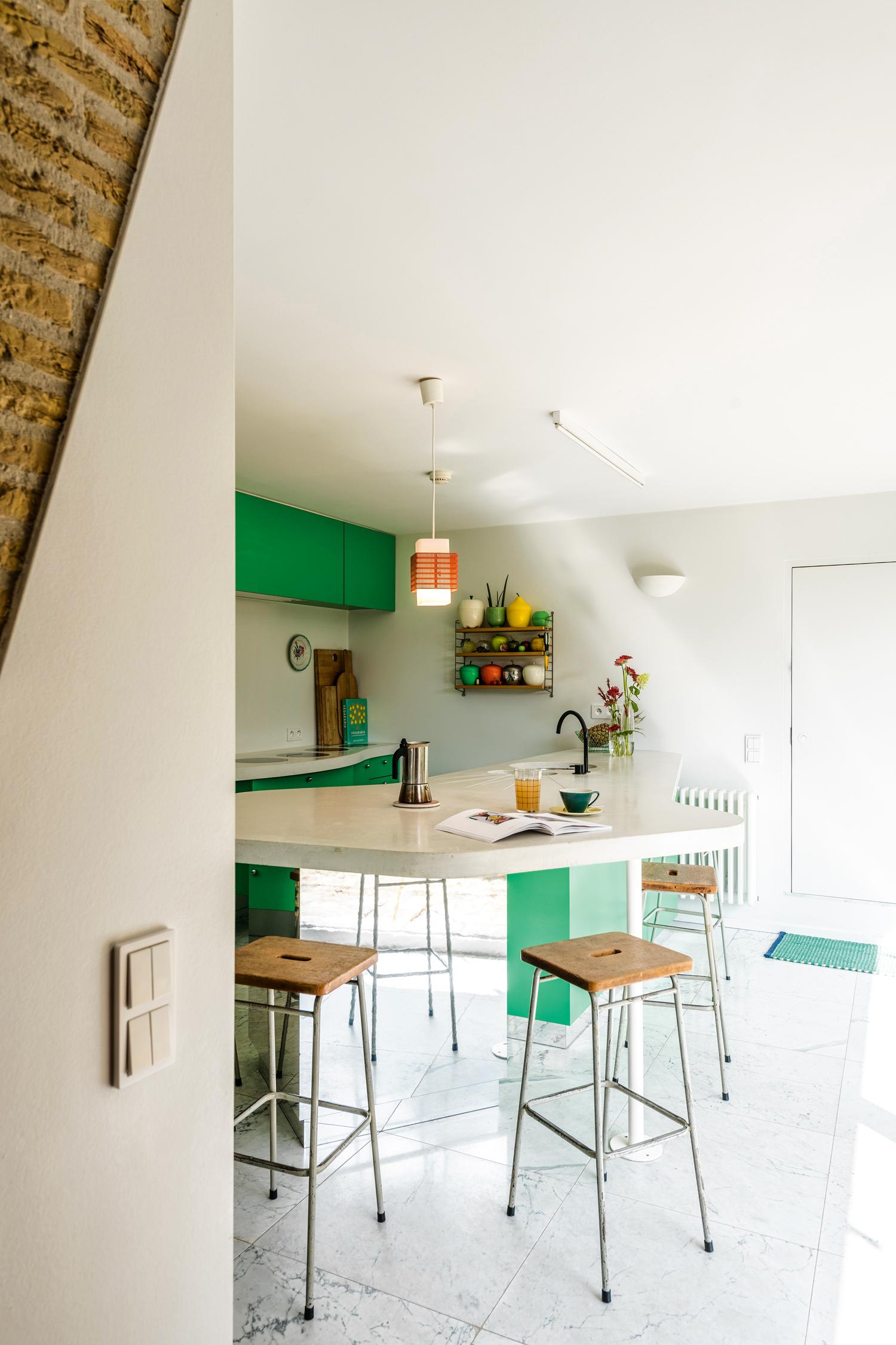 Het organisch vormgegeven keukeneiland in wit beton laat Bogaert toe om overal met haar heupen comfortabel tegen te leunen. Hier ontbijt elke dag het gezin van vier.