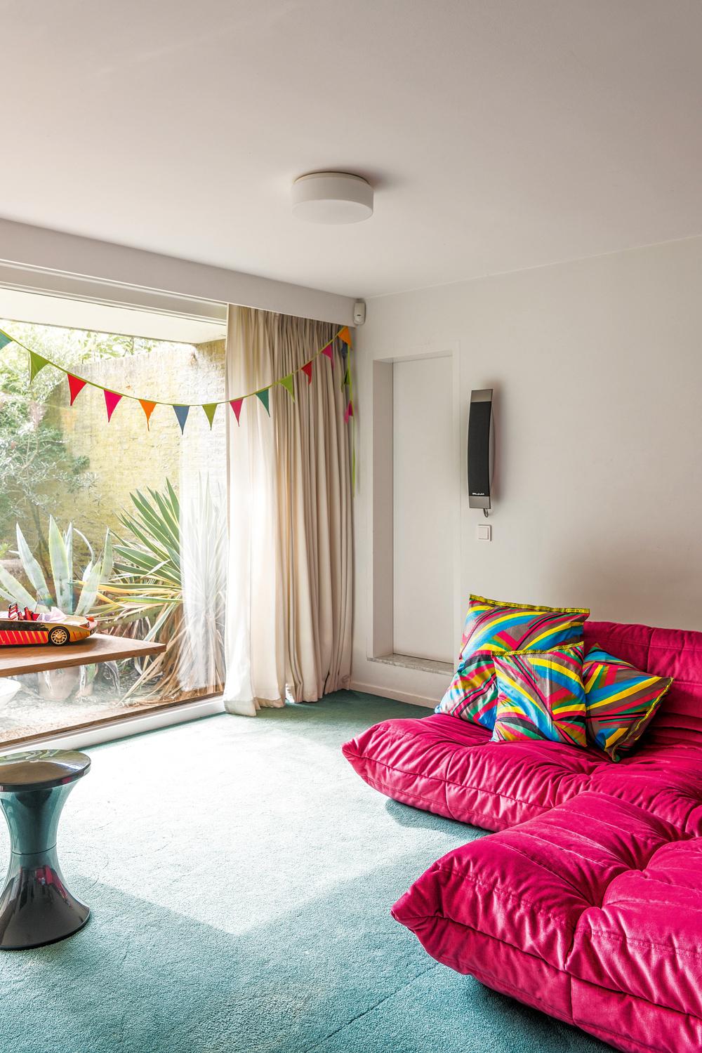 De tv- en speelkamer met roze ‘Togo’-zetels van Ligne Roset kan samen met de logeerkamer op termijn een apart appartement worden.